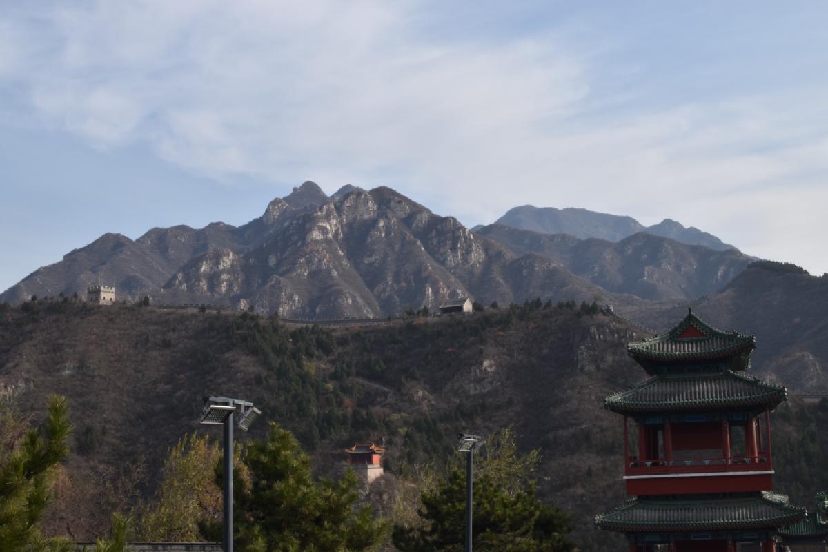 The Great Wall snakes along a ridge below craggy mountains near Beijing, a red pavilion tower in the foreground