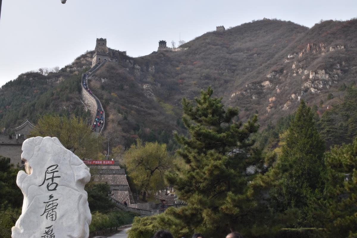 Hikers dot a steep ridge of the Great Wall above a carved white marker stone with Chinese characters
