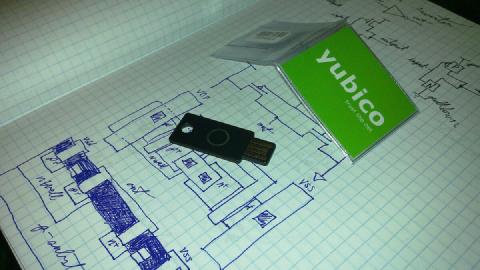 A YubiKey resting on graph paper covered in hand-drawn circuit diagrams